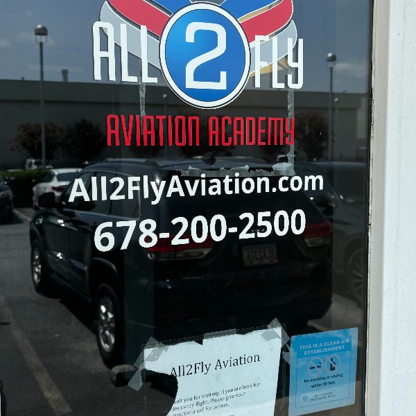 Glass front door with an aviation academy logo, website and phone number