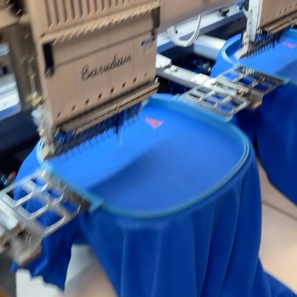 Embroidery machine stitching a logo onto a blue shirt