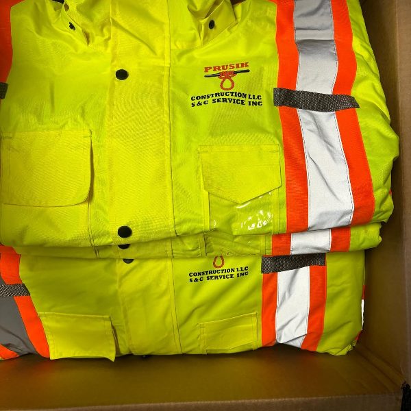 Folded hi-vis yellow jackets with orange and silver reflective stripes and a construction company logo