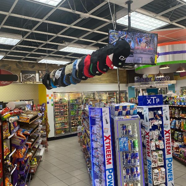 Custom hats hanging on a display above the aisles of a convenience store
